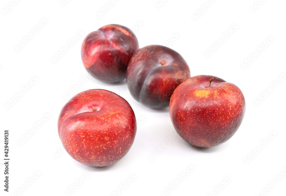 Four large red plums with little yellow dots on white background