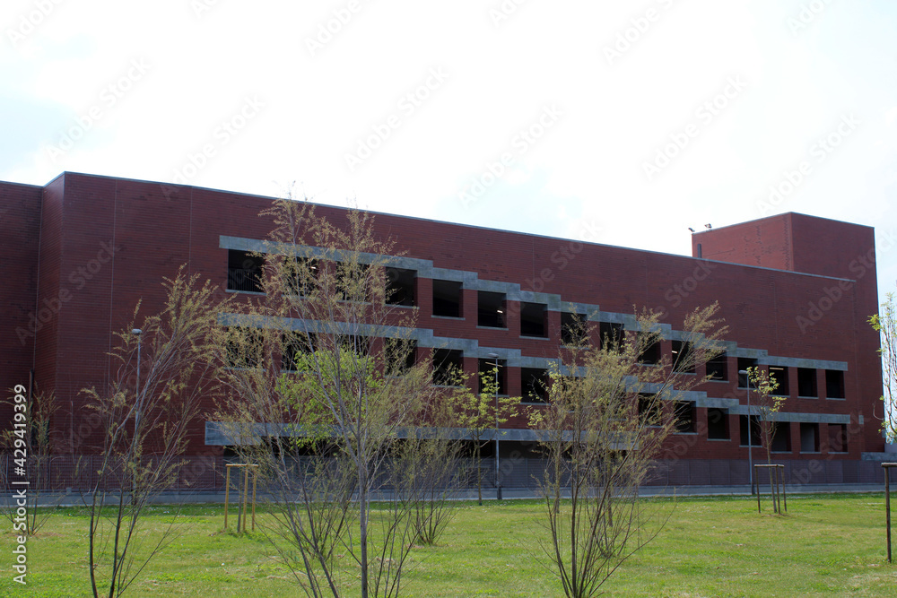 Edificio industriale e parcheggio sopraelevato con prato e alberi Edificio industriale e parcheggio sopraelevato con prato e alberi