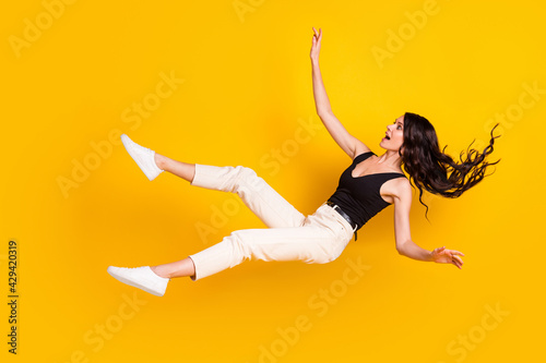 Full length body size photo of woman in stylish outfit falling down shocked amazed isolated on vivid yellow color background photo