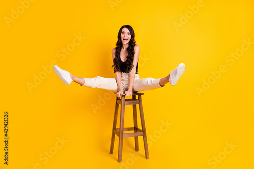 Full body photo of young excited girl happy positive smile playful fooling sit chair isolated over yellow color background