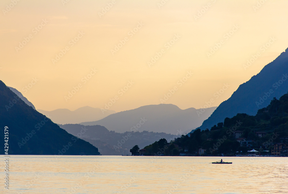 Sunset over lake Lugano between mountains during summer in Porleza, Italy