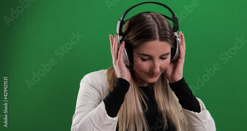 Young pretty woman listens to music on her headphones - studio photography