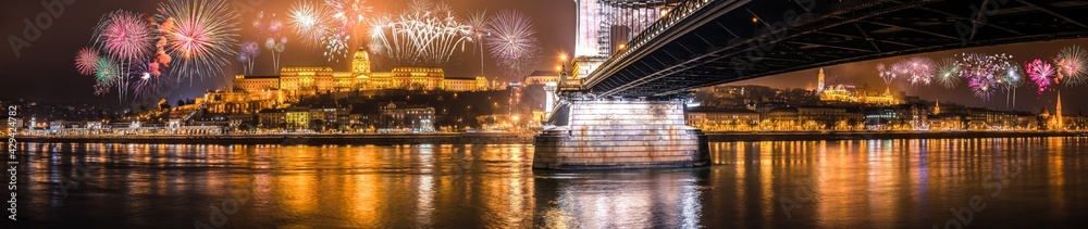 Fototapeta premium Fireworks display at the Royal palace of Buda and the Chain Bridge in Budapest, New Year Eve panorama 