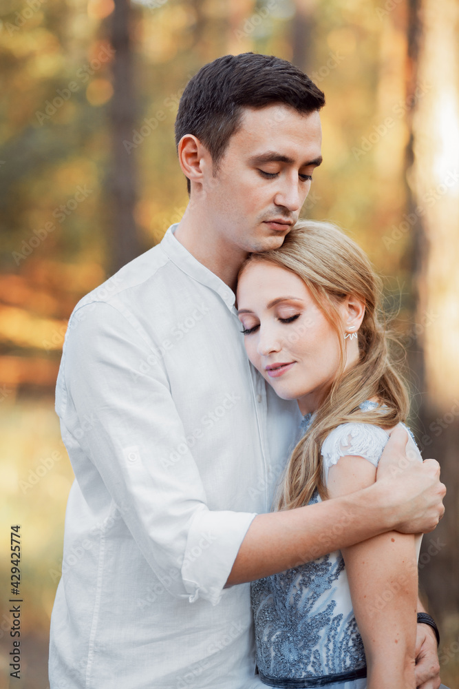 Happy young couple on a walk in the forest at sunset. The bride is wearing a blue wedding dress.