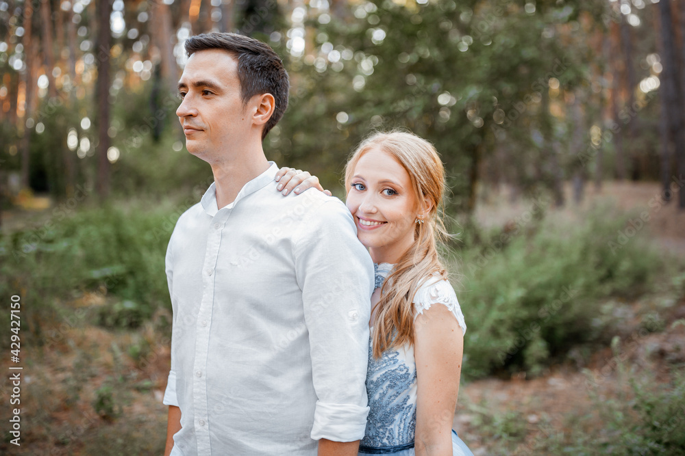 Happy young couple on a walk in the forest at sunset. The bride is wearing a blue wedding dress. Happy young couple on a walk in the forest at sunset. The bride is wearing a blue wedding dress.