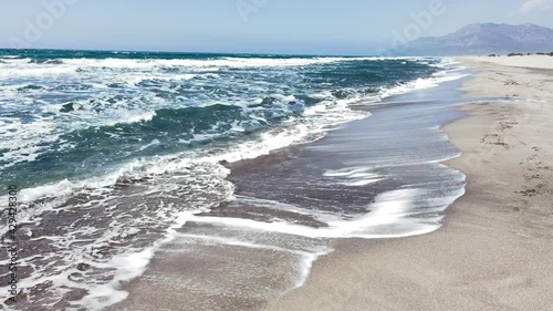 Patara sand dunes washed by Mediterranean Sea waves on white beach with mountains on the background. Vacation concept footage. photo