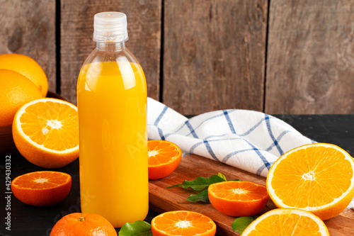 Bottle of orange juice and fresh oranges on table