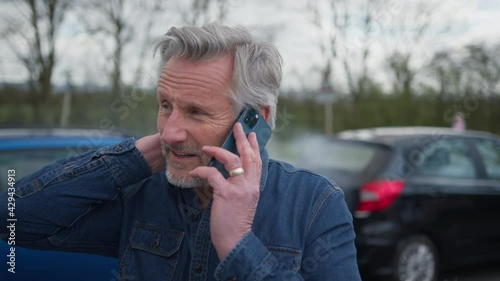 Senior Male Driver With Whiplash Calls Car Insurance Company On Mobile Phone After Traffic Accident