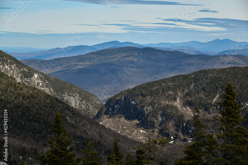 View from Mt. Mansfield Vermont at Stowe ski resort to Notch Path to Smugglers Notch. Late spring time with snow on the mountains and blue sky with clouds.