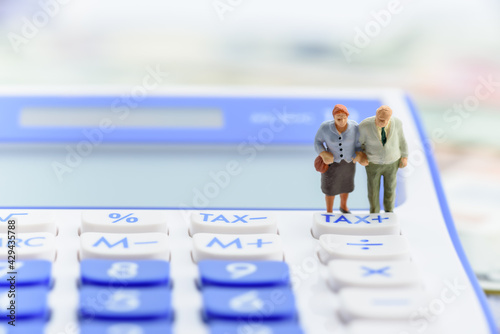 Fotografie Retirement / pension income tax and social security benefit concept : Older american couple stands near a tax button on a calculator, depicts a single largest expense in retirement e
