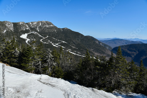 View from Mt. Mansfield Vermont at Stowe ski resort. Late spring time with snow on the mountains and blue sky.