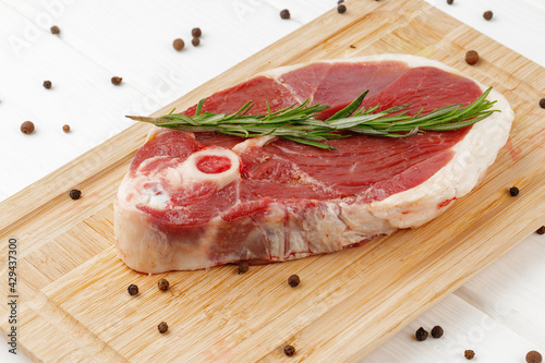 Raw lamb steak on board on white wooden table
