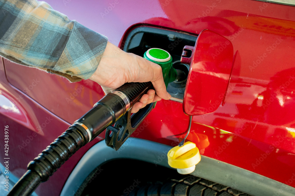 A man hand holding pump filling gasoline into the car. Pumping petrol into the tank. A car refuel on gas station A man hand holding pump filling gasoline into the car. Pumping petrol into the tank. A car refuel on gas station