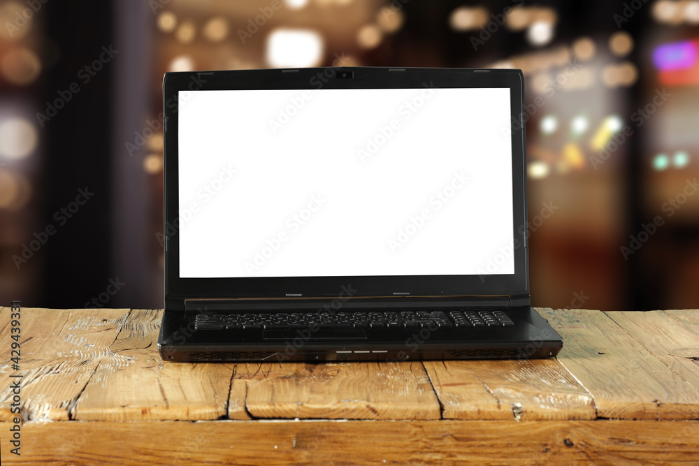 Brown wooden table with black laptop and office interior Brown wooden table with black laptop and office interior