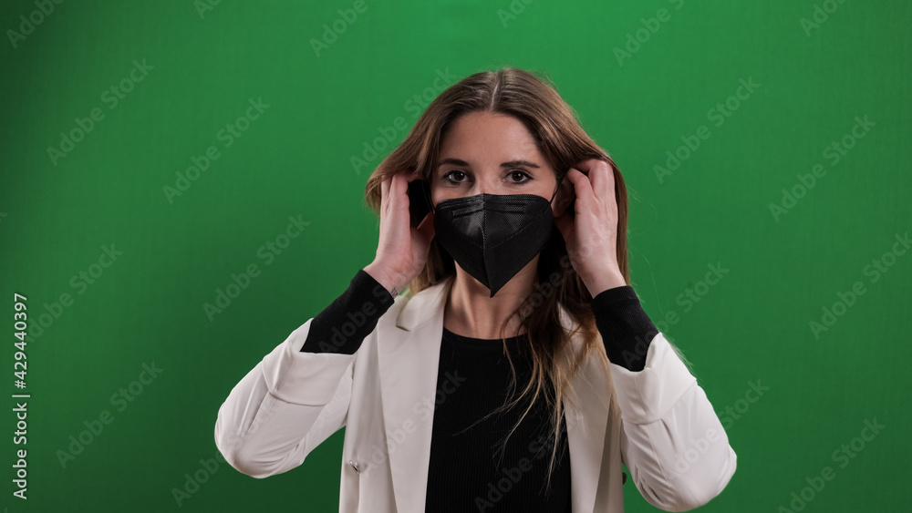 Young woman puts on a medical face mask - studio photography Young woman puts on a medical face mask - studio photography