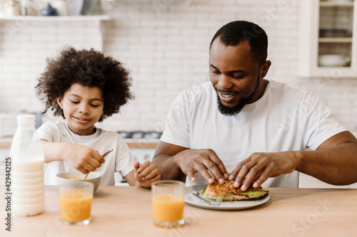Black father and son smiling while having breakfast at home