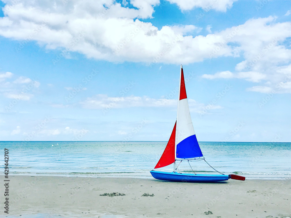Naklejka premium Photo of boat with colorful sails on white sand beach at cloudy weather in north Germany