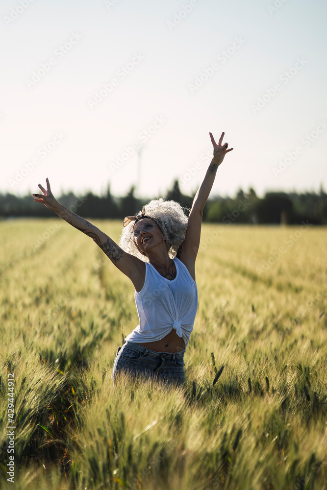 Chica con el pelo muy rizado posando en un campo de trigo Chica con el pelo muy rizado posando en un campo de trigo