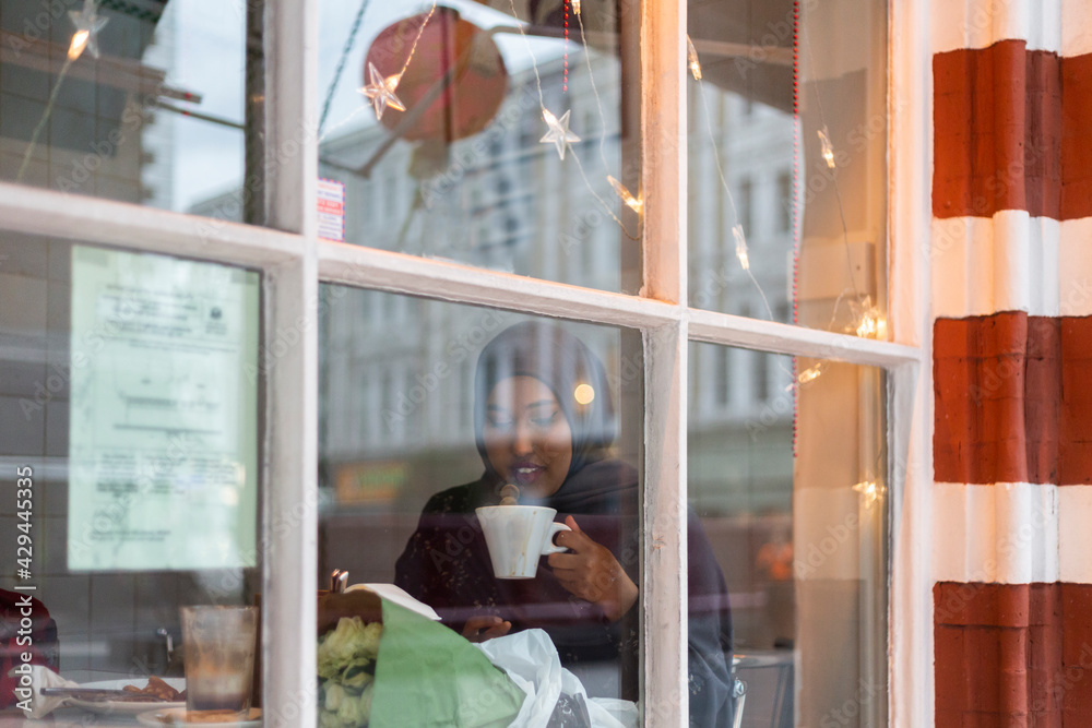 Black Muslim Woman in cafe sipping Black Muslim Woman in cafe sipping