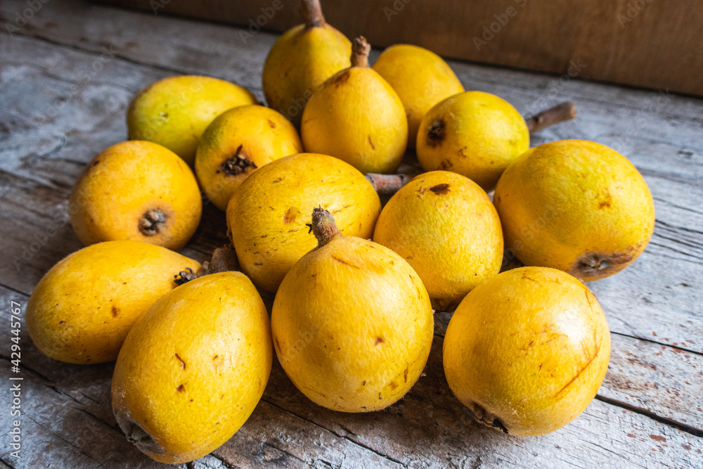 Group of sun-ripened organic loquats on top of a wooden board. Group of sun-ripened organic loquats on top of a wooden board.