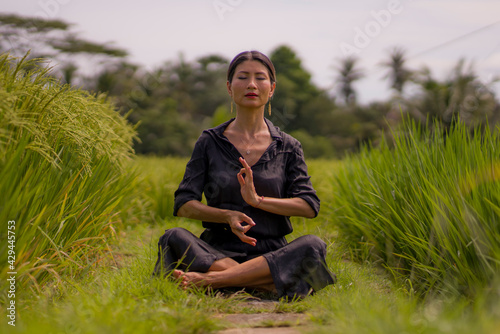 artistic portrait of young attractive and happy Asian woman outdoors at green rice field landscape dancing and doing yoga relaxation exercise and meditation    © TheVisualsYouNeed