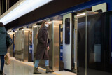 A girl in a surgical face mask is keeping social distance on a subway station.