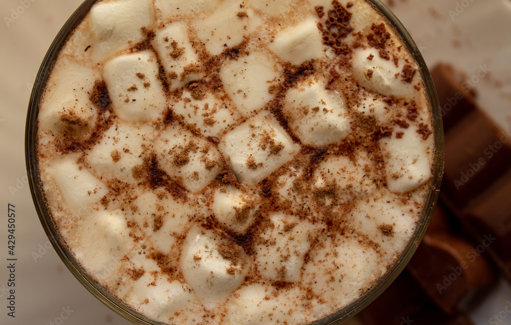 a cup of hot drink, with marshmallows, chocolate and cinnamon. 