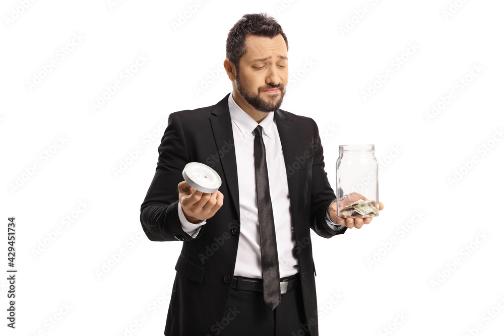 Sad businessman holding a glass jar with coins Sad businessman holding a glass jar with coins