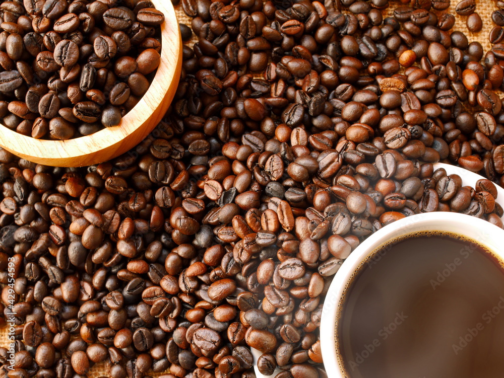 Many coffee beans are between a cup of hot dark coffee and a bowl of coffee beans Many coffee beans are between a cup of hot dark coffee and a bowl of coffee beans