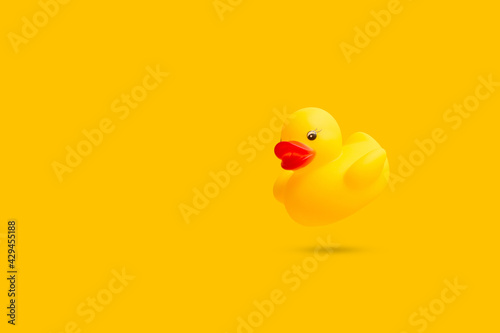 Fotografie Pato de goma amarillo flotando y proyectando sombra sobre un fondo amarillo liso y aislado