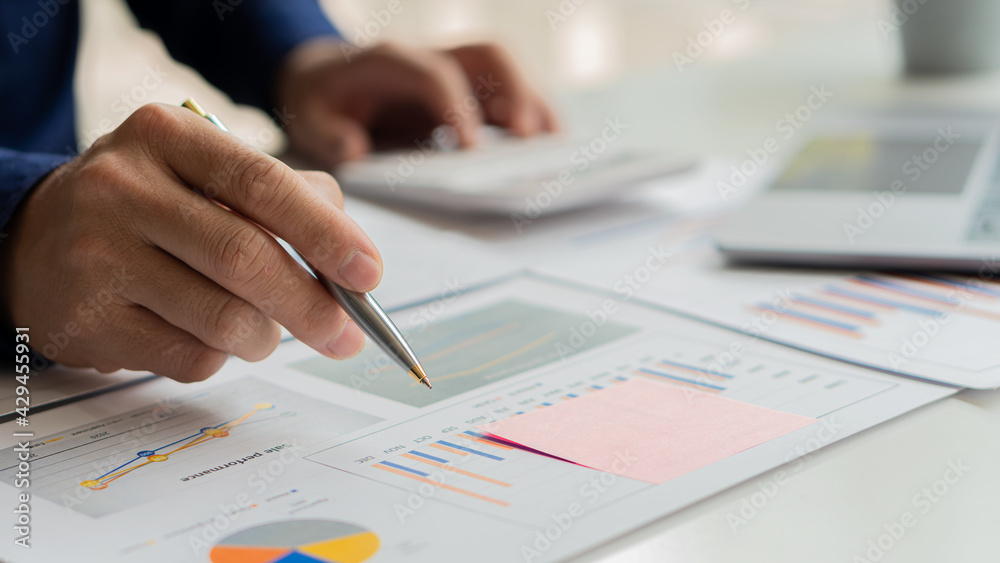 Financial business people calculate with a calculator and graph the cost of investing in real estate.