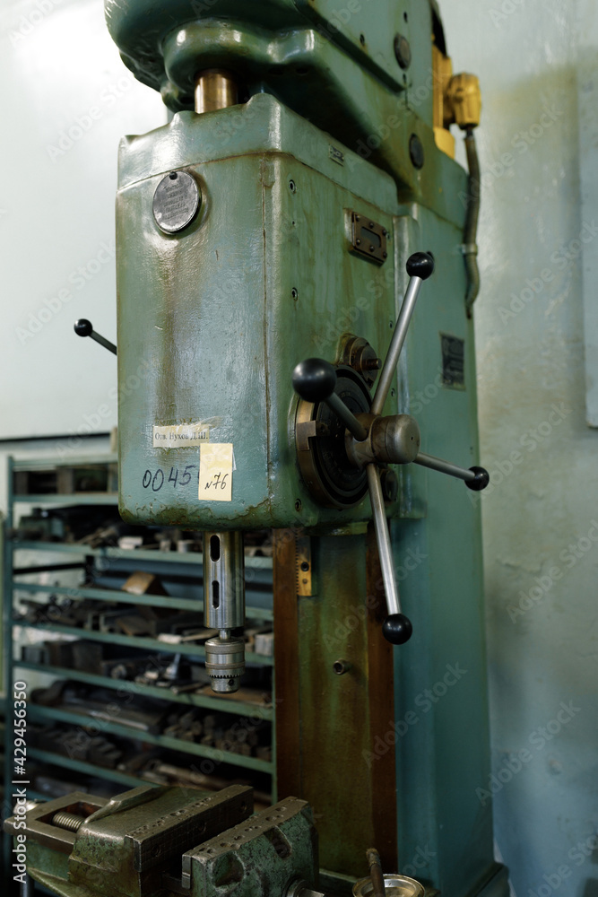 Drilling machine in the old shop. Drilling machine parts and spindle with drills.