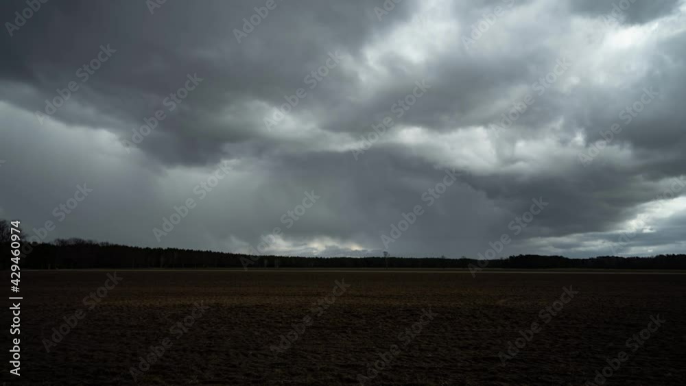 dunkle Wolken über einem Feld im Zeitraffer