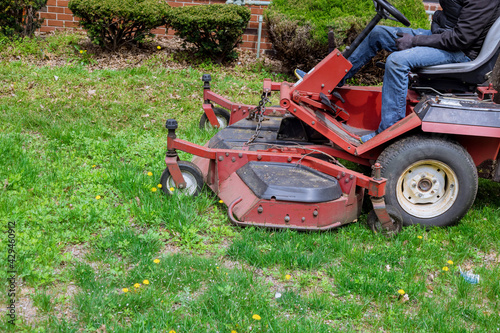 Utility worker in lawn mower gardener cutting the grass ride-on lawnmower