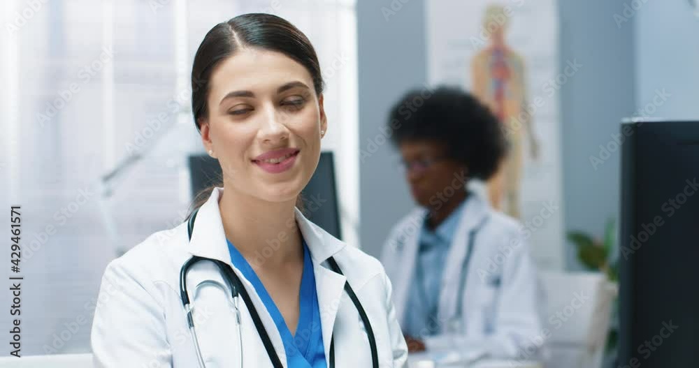 Close up portrait of joyful positive young woman doctor looking at camera and smiling while working in clinic. Happy female healthcare worker in white medical coat with smile on face, medic concept Close up portrait of joyful positive young woman doctor looking at camera and smiling while working in clinic. Happy female healthcare worker in white medical coat with smile on face, medic concept