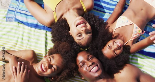 Portrait of african american parents and two children lying on a towel at the beach smiling