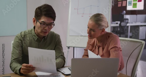 Diverse male and female business colleagues in discussion in meeting room analyzing documents photo