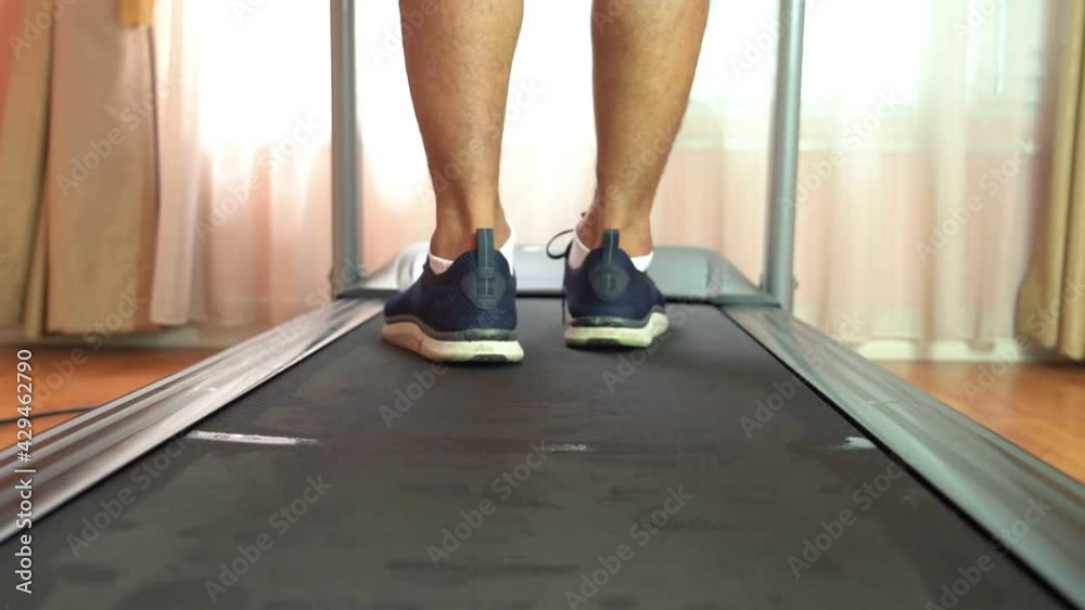 Close-up of a man wearing a blue sports walking on a treadmill in a private room. Concept for exercise, fitness and healthy lifestyle. Close-up of a man wearing a blue sports walking on a treadmill in a private room. Concept for exercise, fitness and healthy lifestyle.