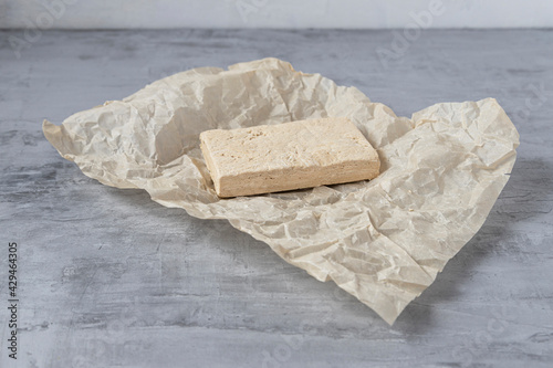 Peanut halva lying on parchment paper on a gray background. Copy space. Traditional national dessert. Turkish, Arabic, Oriental cuisine.