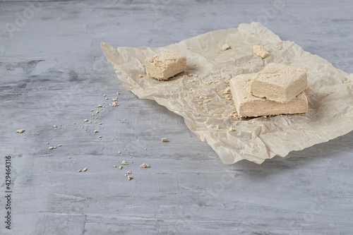 Peanut halva lying on parchment paper on a gray background. Copy space. Traditional national dessert. Turkish, Arabic, Oriental cuisine.