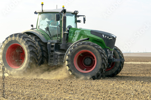 A large tractor with a plow is working in the field. Tillage before sowing. Loosening and plowing the soil before planting wheat and other cereals. Agricultural work.