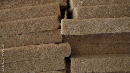 Slow motion pedestal shooting from above to below of sheets of hemp wool, stacked one on top of the other, in an eco friendly house building site. 