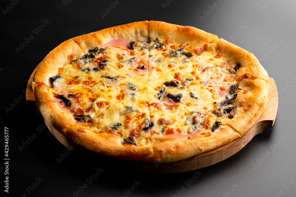 Pizza is not a wooden board. Black background. close-up.