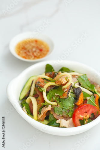 Mixed dried fish with young neem leaves, sliced green mango and sliced tomato - Vietnamese style salad