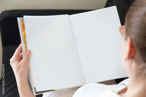 beautiful female hands holding white magazine with blank cover mock up at home