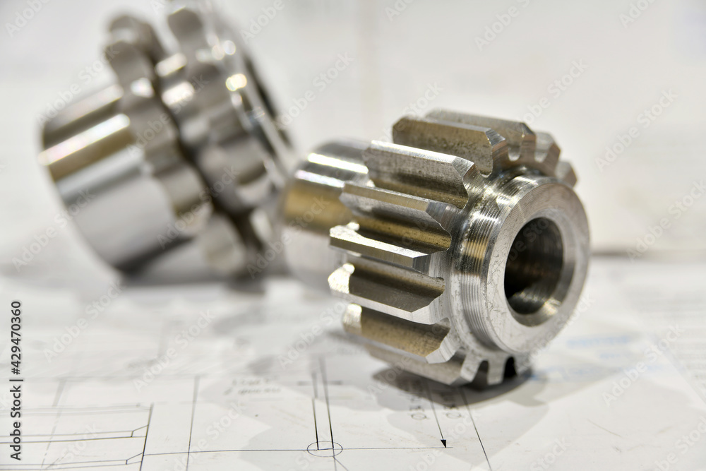 A cogwheel made on a gear cutting machine lies on the technical drawings. A cogwheel made on a gear cutting machine lies on the technical drawings.