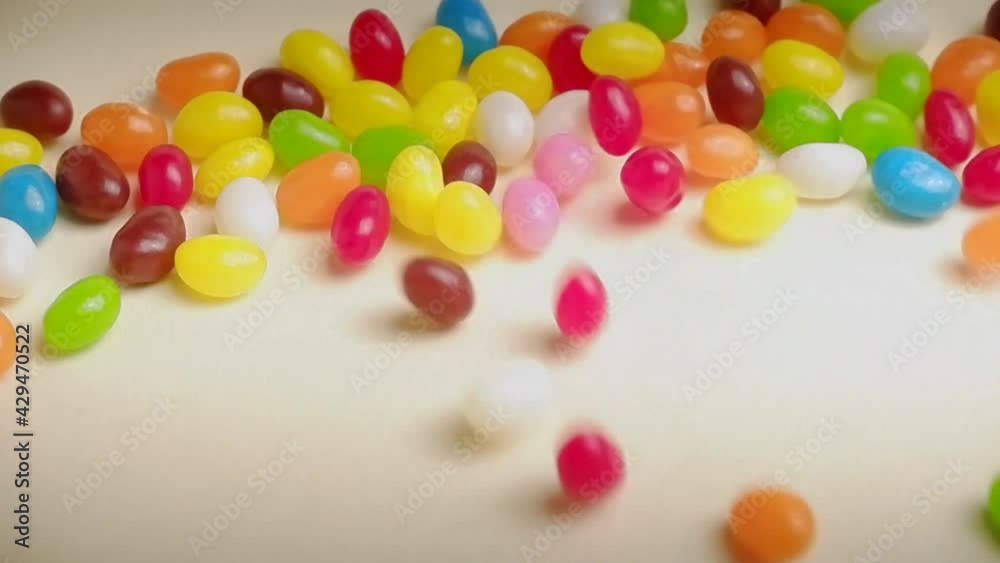 Multicolor Jelly Beans Candy Falls on White Background. Bright Tasty Colourful Texture Of Candy in Slow Motion