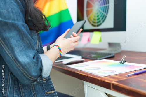Woman in office with cell phone and LGBT accessories. LGBTQIA culture. photo