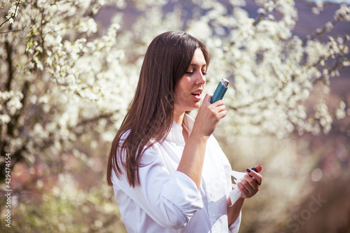 Young woman uses an inhaler outdoor