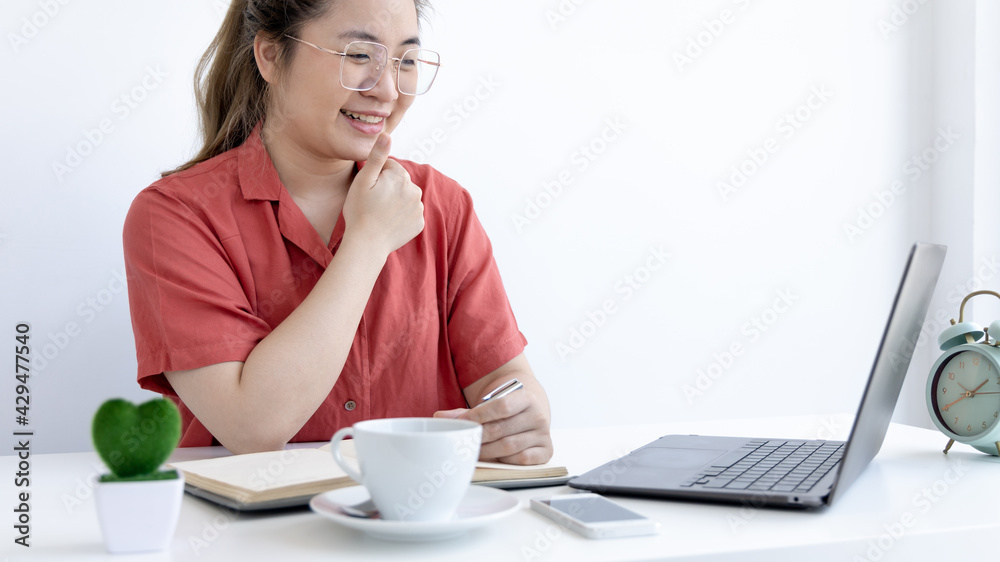 Asian business woman in a bright t-shirt is working at home, Stay home, New normal, Covid-19 coronavirus, Social distancing, Coming up with ideas for work, Writing information in a notebook. Asian business woman in a bright t-shirt is working at home, Stay home, New normal, Covid-19 coronavirus, Social distancing, Coming up with ideas for work, Writing information in a notebook.